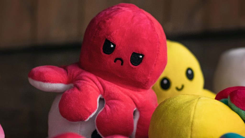 Two plush octopus toys, one with a smiling face and the other with a frown, showing contrasting emotions